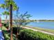 Scenic lake view with a fountain, palm trees, walking path, and meticulously maintained green spaces under a clear blue sky at 7066 Sw 91St Ct, Ocala, FL 34481