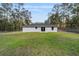 Expansive backyard with lush green grass, neutral grey home exterior and sliding glass door access at 2391 Sw 143 Ct, Ocala, FL 34481