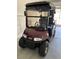 Maroon golf cart with windshield and black top parked in garage at 9350 Sw 91St Court Rd, Ocala, FL 34481