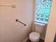 Small bathroom with a toilet and glass block window at 10975 Sw 69Th Cir, Ocala, FL 34476