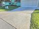 Long concrete driveway leading to an attached two car garage surrounded by green lawns at 10975 Sw 69Th Cir, Ocala, FL 34476