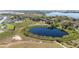 Aerial view of a community pond surrounded by trees, residential area and green space at 547 Tanaro Ln, Haines City, FL 33844