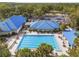 Aerial view of a large outdoor pool area, complete with lounge chairs, tables, and lush tropical landscaping at 10886 Sw 90Th Ter, Ocala, FL 34481