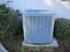 Side view of an outdoor air conditioner surrounded by bushes at 11354 Sw 138Th Pl, Dunnellon, FL 34432