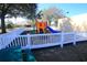 Community playground featuring colorful slides and play structures, enclosed by a charming white picket fence at 16331 Sw 12Th Ter, Ocala, FL 34473