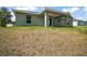 Home's backyard features a covered porch, large windows, and a well-maintained grassy area at 176 Pine Crse, Ocala, FL 34472