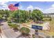 Scenic community entrance with mature landscaping, water features and American flag at 6688 Sw 113Th Pl, Ocala, FL 34476