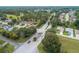 Aerial view of a neighborhood entrance with guard house, gate, trees and residential homes in the distance at 6688 Sw 113Th Pl, Ocala, FL 34476