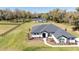 Ariel view of this single-story home shows a well manicured front lawn with white house and dark gray roof at 1725 W Hwy 329, Citra, FL 32113