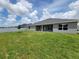 Beautiful backyard with green grass, gray house and white fence under a blue sky and clouds at 8309 Sw 58Th Ave, Ocala, FL 34476