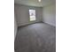 This bedroom has neutral walls, gray carpet, and a window with a white frame at 8309 Sw 58Th Ave, Ocala, FL 34476