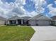 Beautiful single Gathering home featuring a 3-car garage and well-maintained lawn with decorative stone accents at 8309 Sw 58Th Ave, Ocala, FL 34476