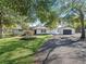 Charming home exterior with lush lawn, mature trees, and blacktop driveway leading to detached garage at 965 Nw 73Rd Ter, Ocala, FL 34482