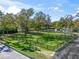 Wide shot of the fenced horse paddock with a lush green lawn, mature trees and the back of the home at 965 Nw 73Rd Ter, Ocala, FL 34482