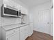 Kitchenette featuring tile floors, white appliances and cabinets, and tile backsplash at 965 Nw 73Rd Ter, Ocala, FL 34482