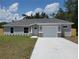 Charming single-story home with a gray exterior, manicured lawn, and a concrete driveway leading to a one-car garage at 13441 Sw 113Th Pl, Dunnellon, FL 34432