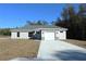 One-story house with gray siding, white garage door, and a stone accent at 13441 Sw 113Th Pl, Dunnellon, FL 34432