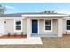 A single-story home with a neutral exterior, blue front door, white trim, and a manicured lawn at 1877 Sw 150 Ct, Ocala, FL 34481