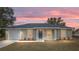 A single-story home featuring a blue front door, white garage door, well-manicured lawn at sunset at 1877 Sw 150 Ct, Ocala, FL 34481