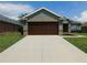 Charming home with a brown two-car garage, a concrete driveway, and manicured landscaping at 4085 Sw 49Th Ave, Ocala, FL 34474