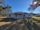 Backyard featuring a covered patio and expansive yard with mature trees against a clear blue sky at 7605 Sw 103Rd Loop, Ocala, FL 34476