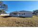 Back of house showing patio, lawn, and stucco walls under a brilliant blue sky at 7613 Sw 103Rd Loop, Ocala, FL 34476