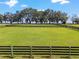 Large grassy paddock with wooden fencing at 8544 Nw 160Th Ave, Morriston, FL 32668