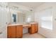 Bathroom with double sink vanity with wood cabinets, mirror, and a window allowing natural light at 4950 Sw 45Th Cir, Ocala, FL 34474