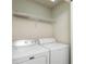 Functional laundry area with a side-by-side washer and dryer, and overhead shelving for added convenience at 4950 Sw 45Th Cir, Ocala, FL 34474