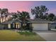 Charming single-story home with lush front yard and two-car garage beneath a colorful dusk sky at 8448 Se 161St St, Summerfield, FL 34491