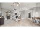 Open-concept living room featuring neutral tones, tile floors, and modern light fixtures with an adjacent kitchen at 8448 Se 161St St, Summerfield, FL 34491