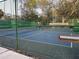 Outdoor community tennis court surrounded by green fence and trees at 10819 Sw 84Th Ter, Ocala, FL 34481