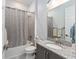 Well-lit bathroom featuring a shower with a tub, neutral-patterned shower curtain, granite countertop, and modern sink at 31771 Red Tail Blvd, Sorrento, FL 32776