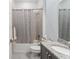 Well-lit bathroom featuring a shower with a tub, neutral-patterned shower curtain, granite countertop, and modern sink at 31771 Red Tail Blvd, Sorrento, FL 32776