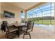 Inviting covered patio with a dining table, grill, and serene views of the pool and backyard through a screen enclosure at 31771 Red Tail Blvd, Sorrento, FL 32776