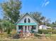 Charming single-story home with a teal metal roof, manicured lawn, and mature trees in a picturesque setting at 26 Hemlock Cir, Ocala, FL 34472