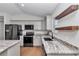 Modern kitchen featuring stainless steel appliances, stone countertops, and stylish floating shelves at 3496 Sw 149Th Ct, Ocala, FL 34481
