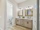 Well-lit bathroom with double vanity, wood-look floors, framed mirrors, and an adjacent toilet room at 4522 Shockoe Cir, The Villages, FL 32163