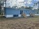 Home featuring a blue exterior, white trim, and a wooden staircase at 11605 Nw 20Th St, Ocala, FL 34482