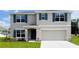 Two-story home featuring blue shutters, a manicured lawn, and a two-car garage at 9989 Se 161St Lane Rd, Summerfield, FL 34491