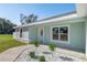 Front entrance of the home, showcasing landscaping and a light teal exterior at 14462 Se 28Th Ct, Summerfield, FL 34491