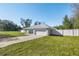 Front view of a newly built home with a light teal exterior, white fence, and a driveway at 14462 Se 28Th Ct, Summerfield, FL 34491