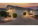 Exterior view of a single story home with a two car garage and manicured front yard at sunset at 1673 Belle Grove Dr, The Villages, FL 32162