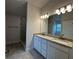 Bathroom showcasing double sinks with granite countertops, a glass-enclosed shower, and modern lighting at 4477 Sw 90Th Pl, Ocala, FL 34476