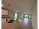 Open-concept living room featuring a kitchen view, tile floors, natural lighting, and a backyard door at 4477 Sw 90Th Pl, Ocala, FL 34476