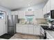 Well-equipped kitchen with white cabinetry, stainless steel appliances, and a view from the window at 816 Hibiscus Dr, The Villages, FL 32159