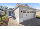 New home exterior with gray siding, white garage door, and brick walkway at 10282 Sw 99Th Ln, Ocala, FL 34481