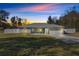 Charming one-story house with light blue exterior, white garage door, and well-manicured lawn at dusk at 14366 Se 27Th Ct, Summerfield, FL 34491