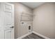 Simple laundry room with white door, wire shelving, and gray flooring at 14366 Se 27Th Ct, Summerfield, FL 34491