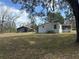 Exterior view of the home with a metal roof, utility building and a spacious yard at 11064 Ne 212Th Ln, Fort Mc Coy, FL 32134